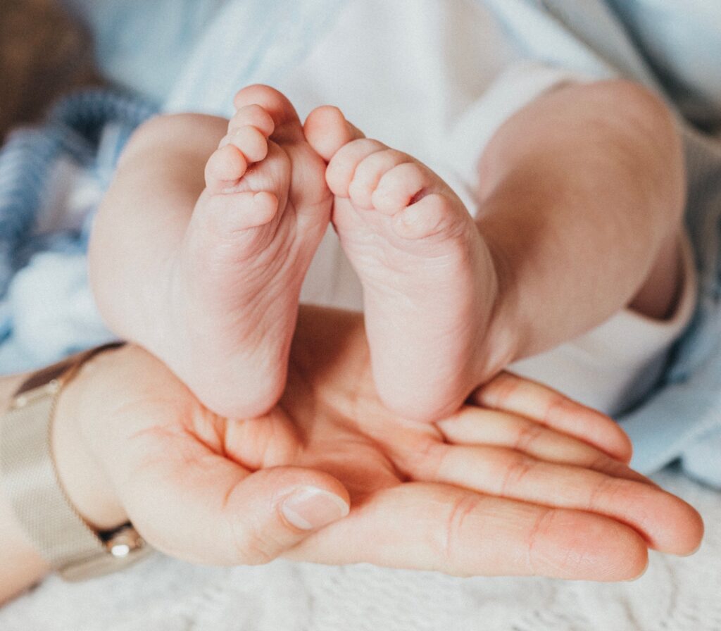 Close-up of baby feet gently held in an adult's hands, symbolizing care and tenderness.